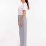 Frau seitlich in grauer orthopädischer Behandlungshose mit elastischem Bund und geschlossenen Druckknöpfen