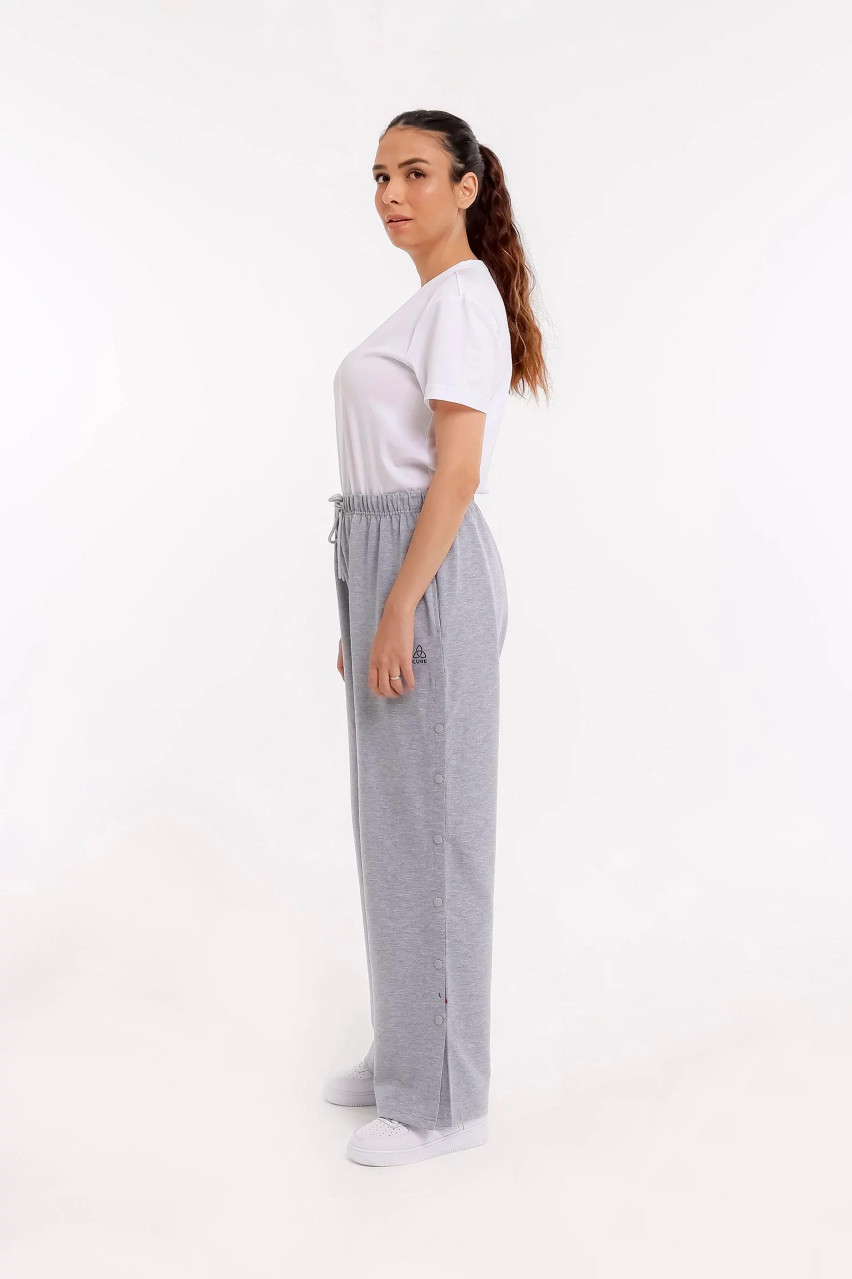 Frau seitlich in grauer orthopädischer Behandlungshose mit elastischem Bund und geschlossenen Druckknöpfen