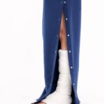 Bein mit Gipsverband unter geöffneter orthopädischer Behandlungshose – zeigt Druckknopföffnung für medizinischen Zugang