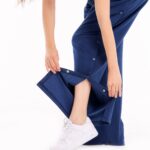 Frau zeigt Funktion der orthopädischen Behandlungshose mit seitlichem Druckknopfverschluss in Blau – für Reha und postoperative Pflege geeignet