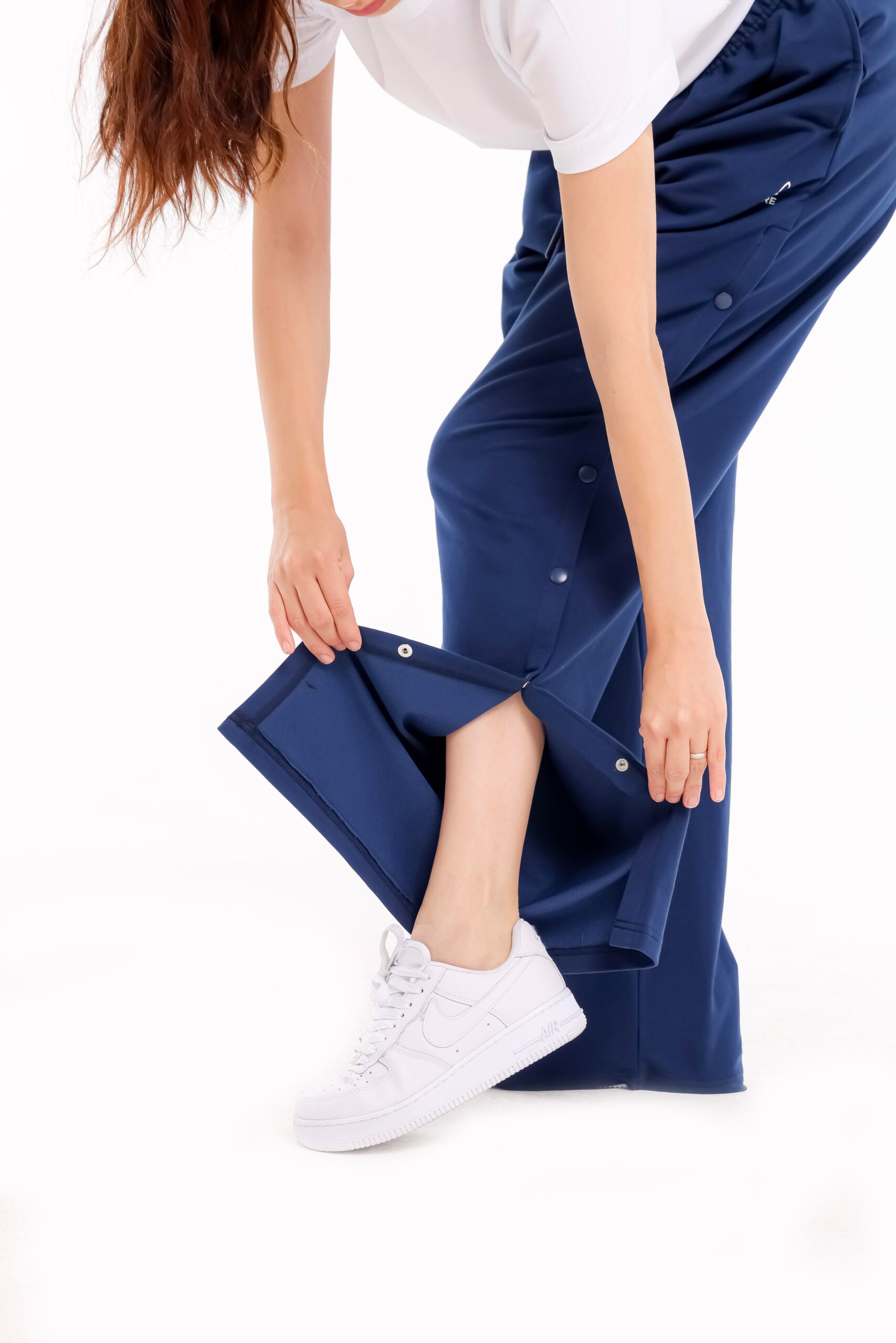Frau zeigt Funktion der orthopädischen Behandlungshose mit seitlichem Druckknopfverschluss in Blau – für Reha und postoperative Pflege geeignet