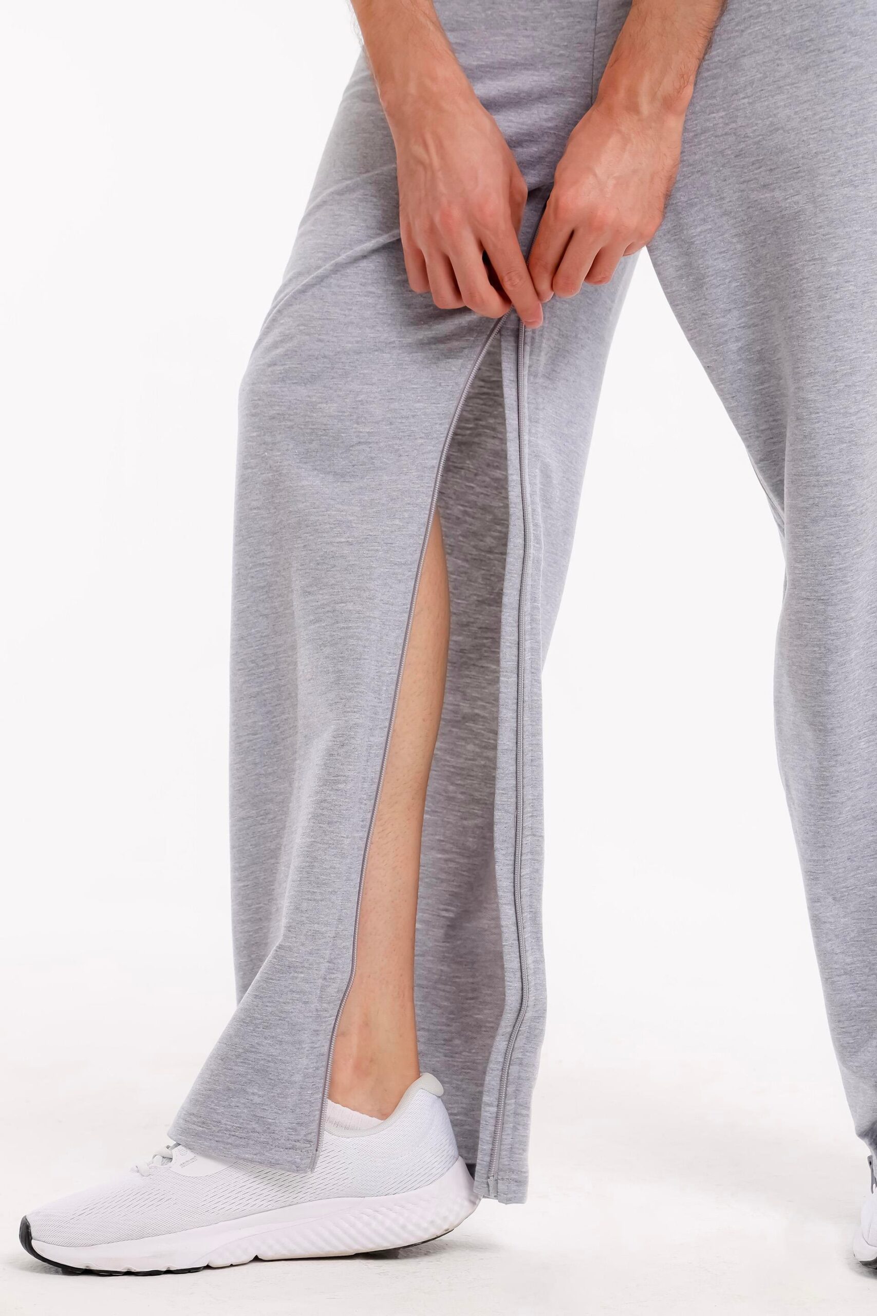 Detailansicht der Pflegehose mit geöffnetem Reißverschluss, der an der Seite heruntergezogen wird.