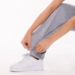 Detailaufnahme einer Person, die den seitlichen Reißverschluss der stationären Pflegehose an der Beinöffnung schließt